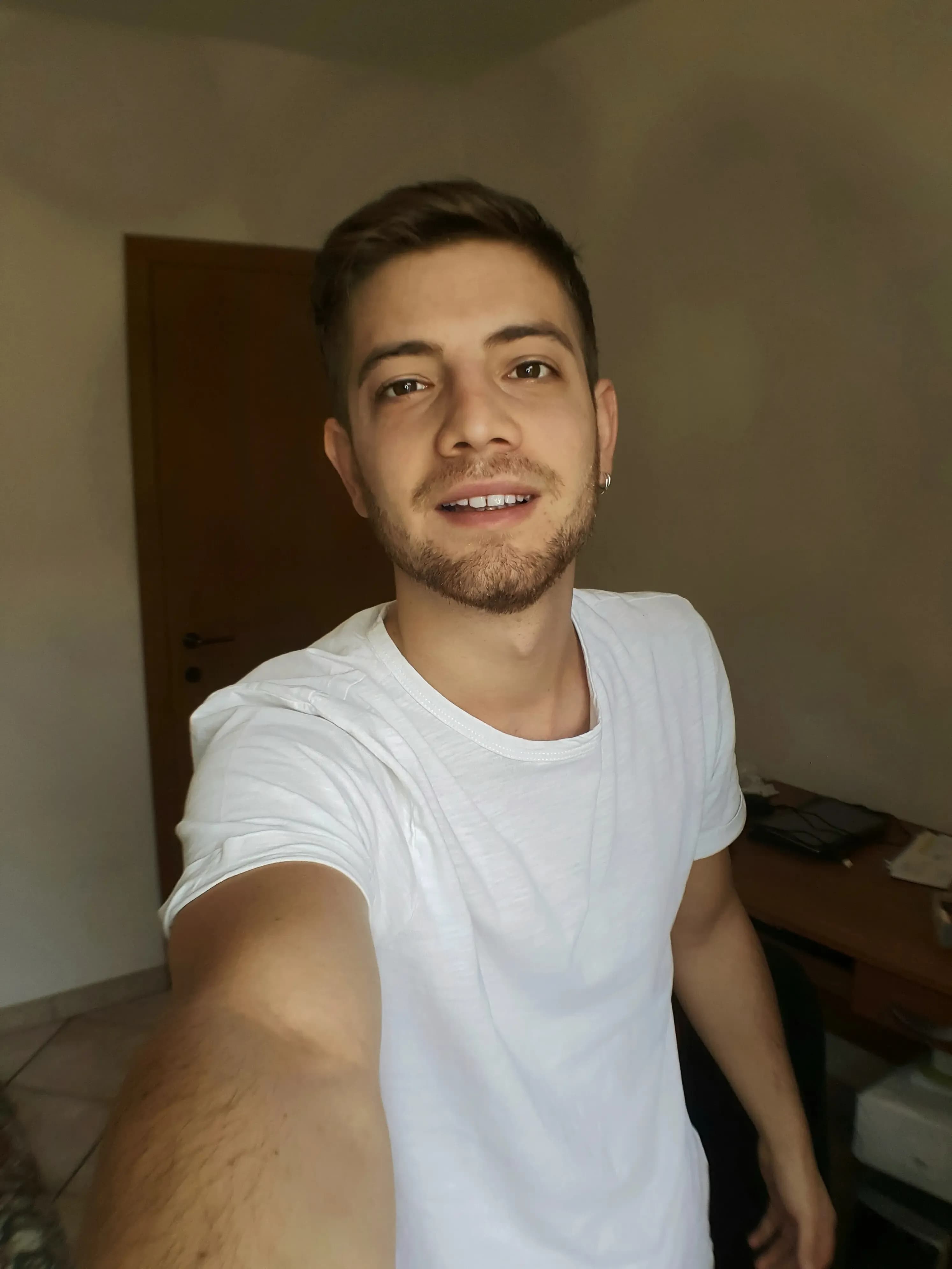 Indoor selfie of a young man wearing a white T-shirt, suitable for generating GTA-inspired AI artwork.